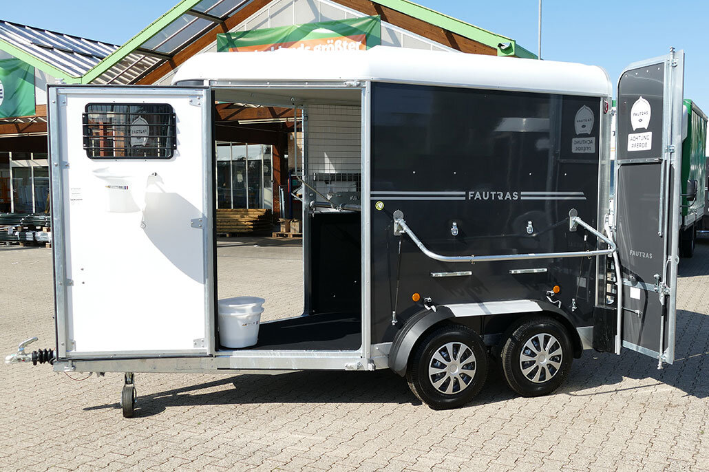 Der Promax Premium Pferdeanhänger in schwarz von außen geöffnet. Mit asugeklappter Halterung und Futterschale die an der Tür befestigt ist.